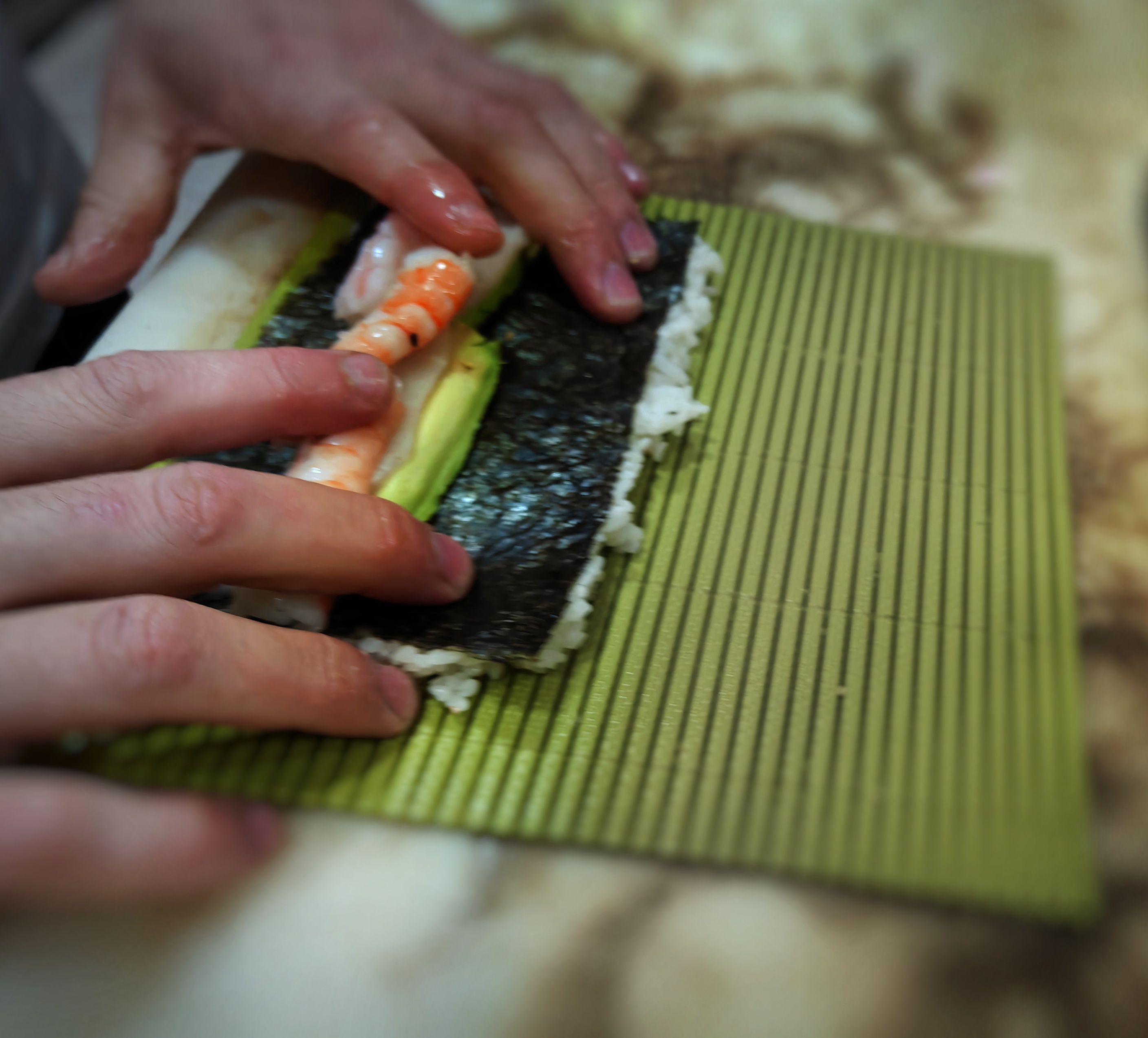 Sushiman haciendo uramaki de aguacate y gambas sobre makisu sudare de Hasegawa en Tanuki San